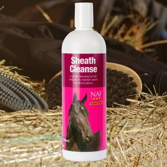 NAF Sheath Cleanse bottle for horses with a horse's head on the label, set against a hay and grooming tools background.