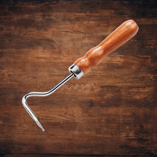 Wooden-handled hoof pick horse grooming tool on a wooden background
