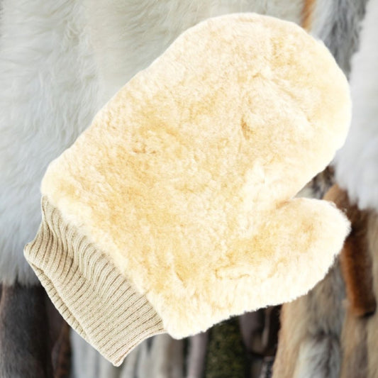 Beige sheepskin grooming mitt for horses with textured surface on a blurred background